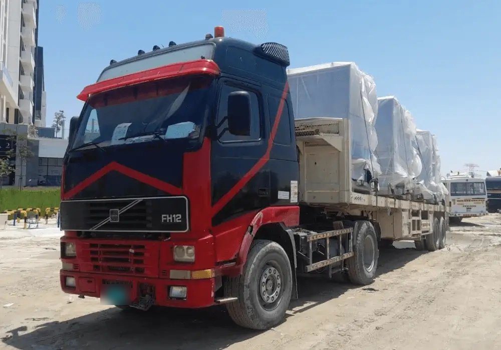 Skyline flatbed truck loaded with wrapped machinery at a UAE site